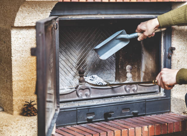 Male hand pour the ashes in the fireplace of the small blades in a large